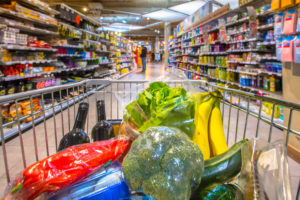 Grocery cart in supermarket filled with food products seen from the customers point of view
